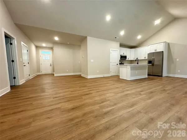 a view of a kitchen with kitchen island wooden floors appliances and cabinets