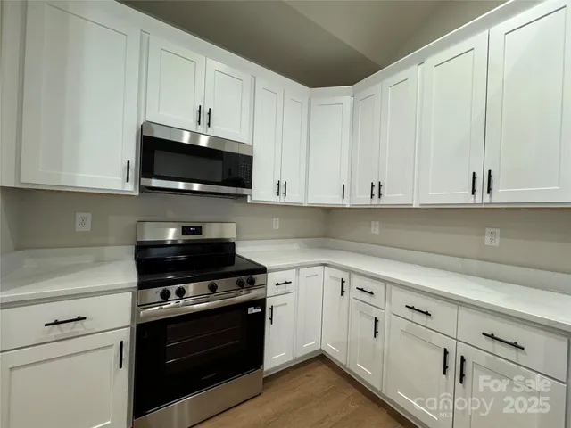 a kitchen with white cabinets and black appliances