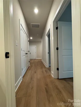 a view of a hallway with wooden floor and a bathroom