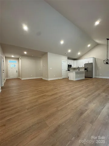 a view of large and white kitchen with wooden floor