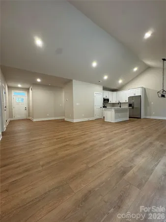 a view of large and white kitchen with wooden floor