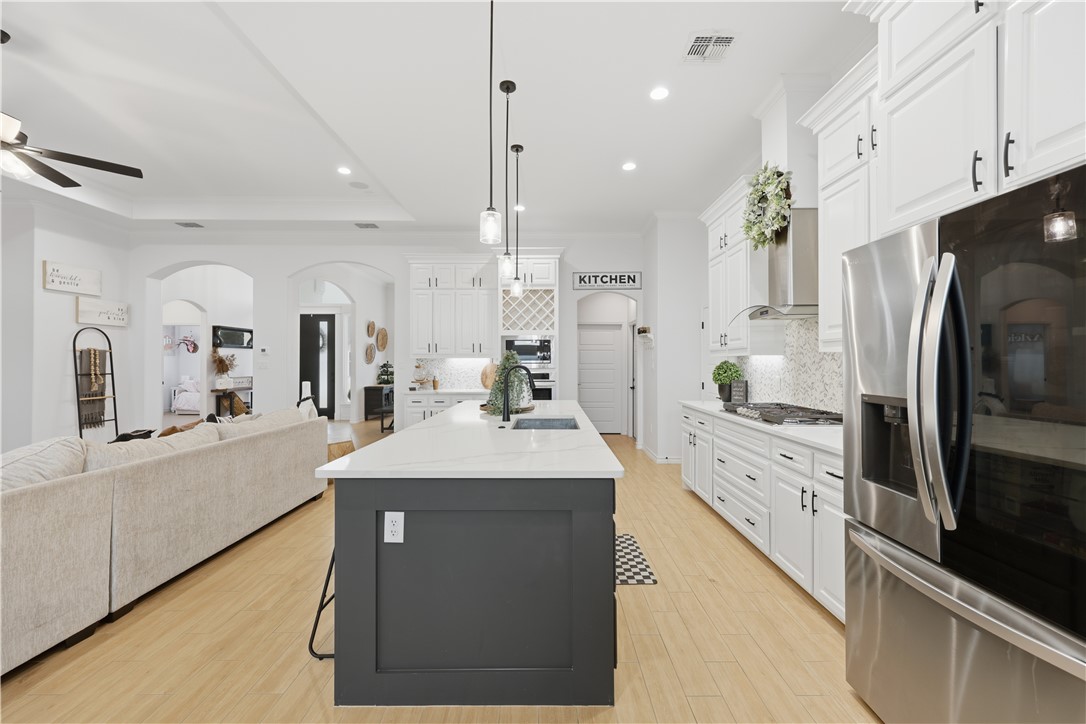 105 Sapphire Street Portland, TX 78374 - Photo 12 of 29 a kitchen with stainless steel appliances kitchen island granite countertop a refrigerator a sink dishwasher and white cabinets with wooden floor