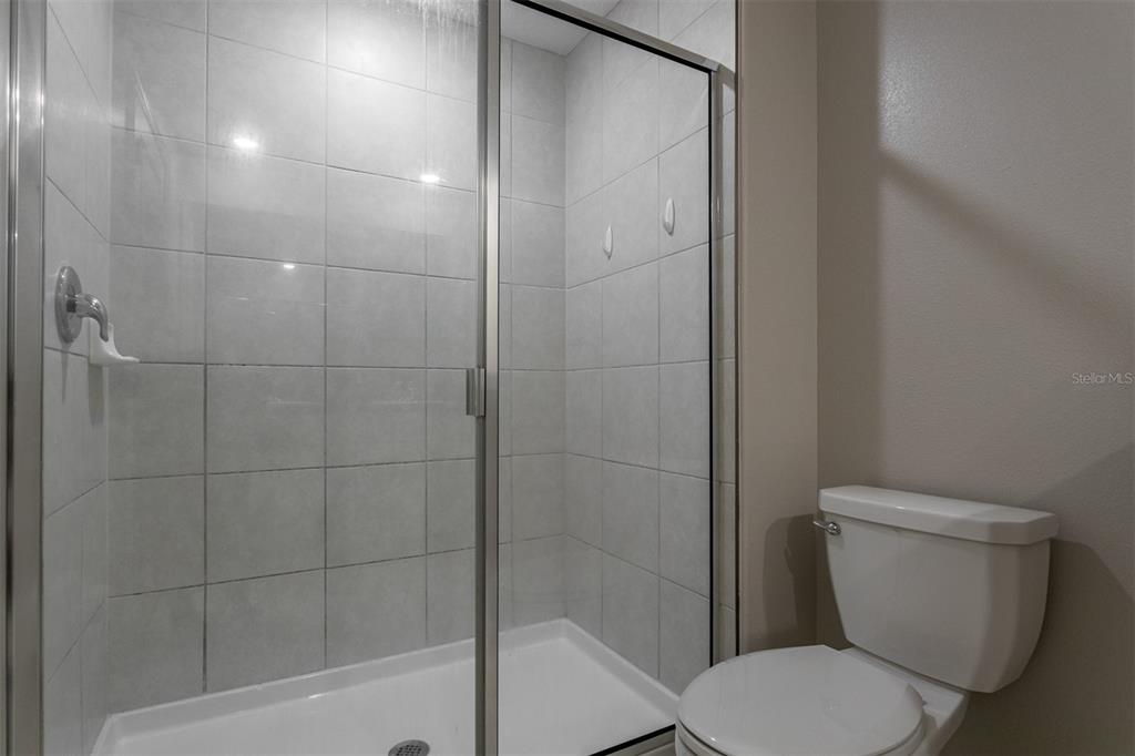14206 Easy Goer Street Ruskin, FL 33573 - Photo 19 of 28 a white toilet sitting next to a bath tub and shower