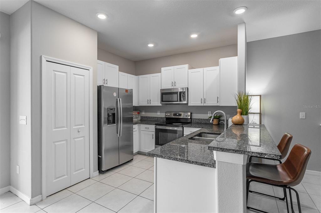 14206 Easy Goer Street Ruskin, FL 33573 - Photo 5 of 28 a kitchen with stainless steel appliances granite countertop a refrigerator oven a sink a stove a dining table and chairs