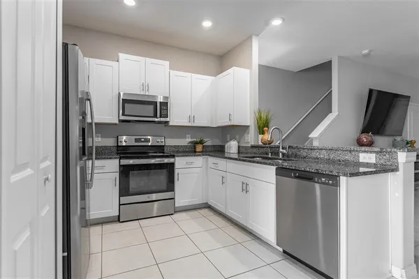 a kitchen with stainless steel appliances granite countertop a stove microwave and sink