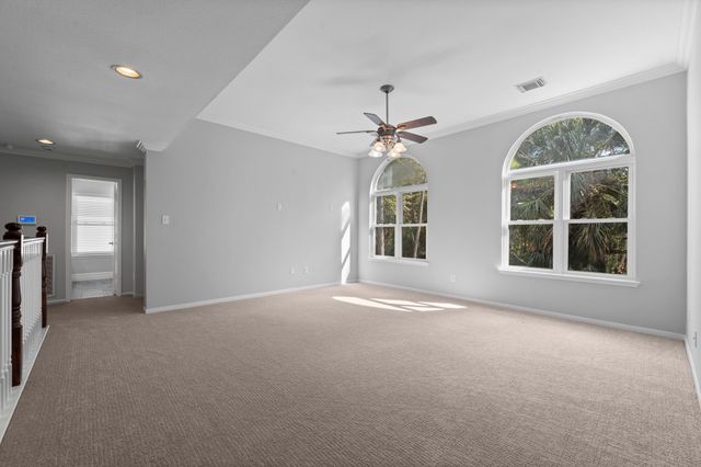 an empty room with windows and chandelier fan