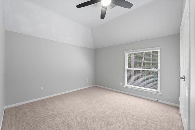 an empty room with a chandelier fan and windows