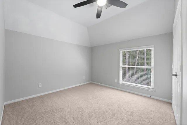 an empty room with a chandelier fan and windows