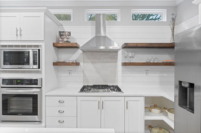 a kitchen with stainless steel appliances a stove and white cabinets