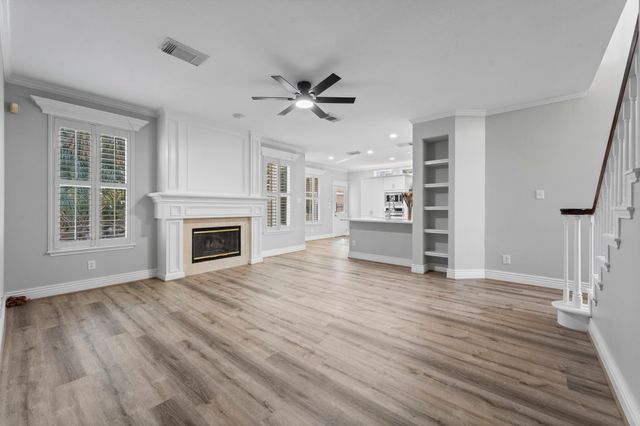a view of a livingroom with a fireplace a ceiling fan and windows