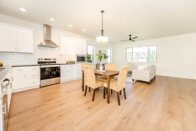 a kitchen with stainless steel appliances kitchen island granite countertop a stove a sink a dining table and chairs