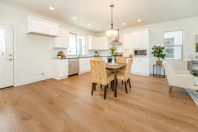 a view of a dining room and livingroom with furniture wooden floor kitchen view