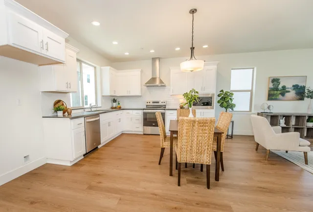a kitchen with stainless steel appliances kitchen island granite countertop a table chairs and a refrigerator