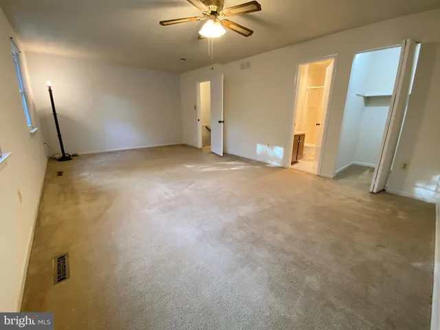 an empty room with closet and a ceiling fan