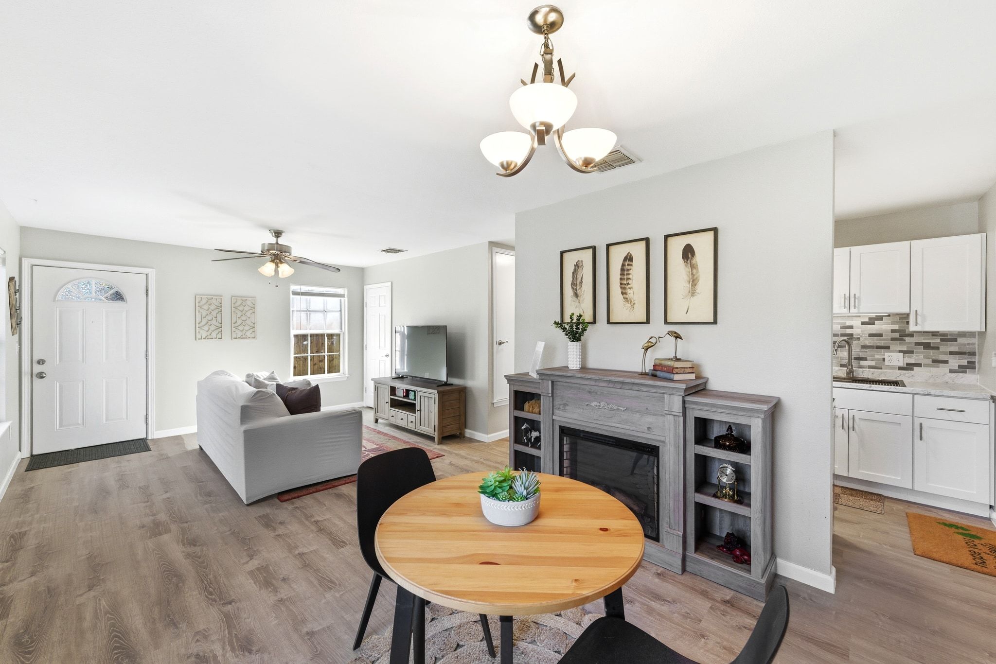 4615 Munson Street Austin, TX 78721 - Photo 1 of 1 Dining room with a glass covered fireplace, light wood-style floors, a chandelier, and a ceiling fan