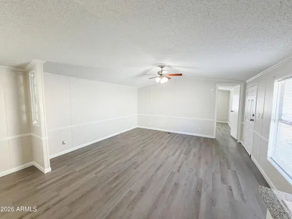 a view of an empty room with wooden floor and a ceiling fan