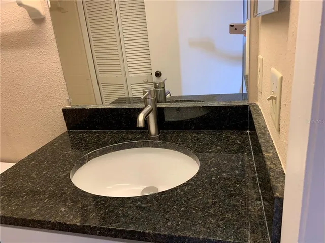 a bathroom with a granite countertop sink and a mirror