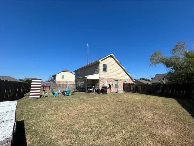 a view of a house with a yard and lawn chairs