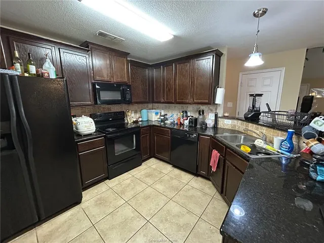 a kitchen with stainless steel appliances granite countertop a refrigerator a sink a stove a microwave and wooden cabinets