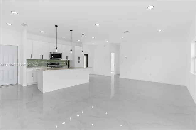 a kitchen with granite countertop a stove a sink and a refrigerator