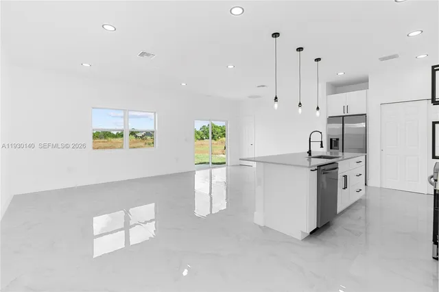 a kitchen with granite countertop a stove a sink and a refrigerator