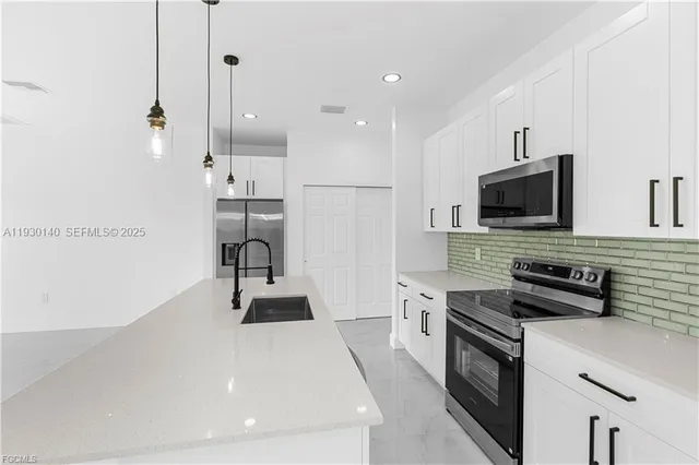 a kitchen with granite countertop a stove a sink and a refrigerator
