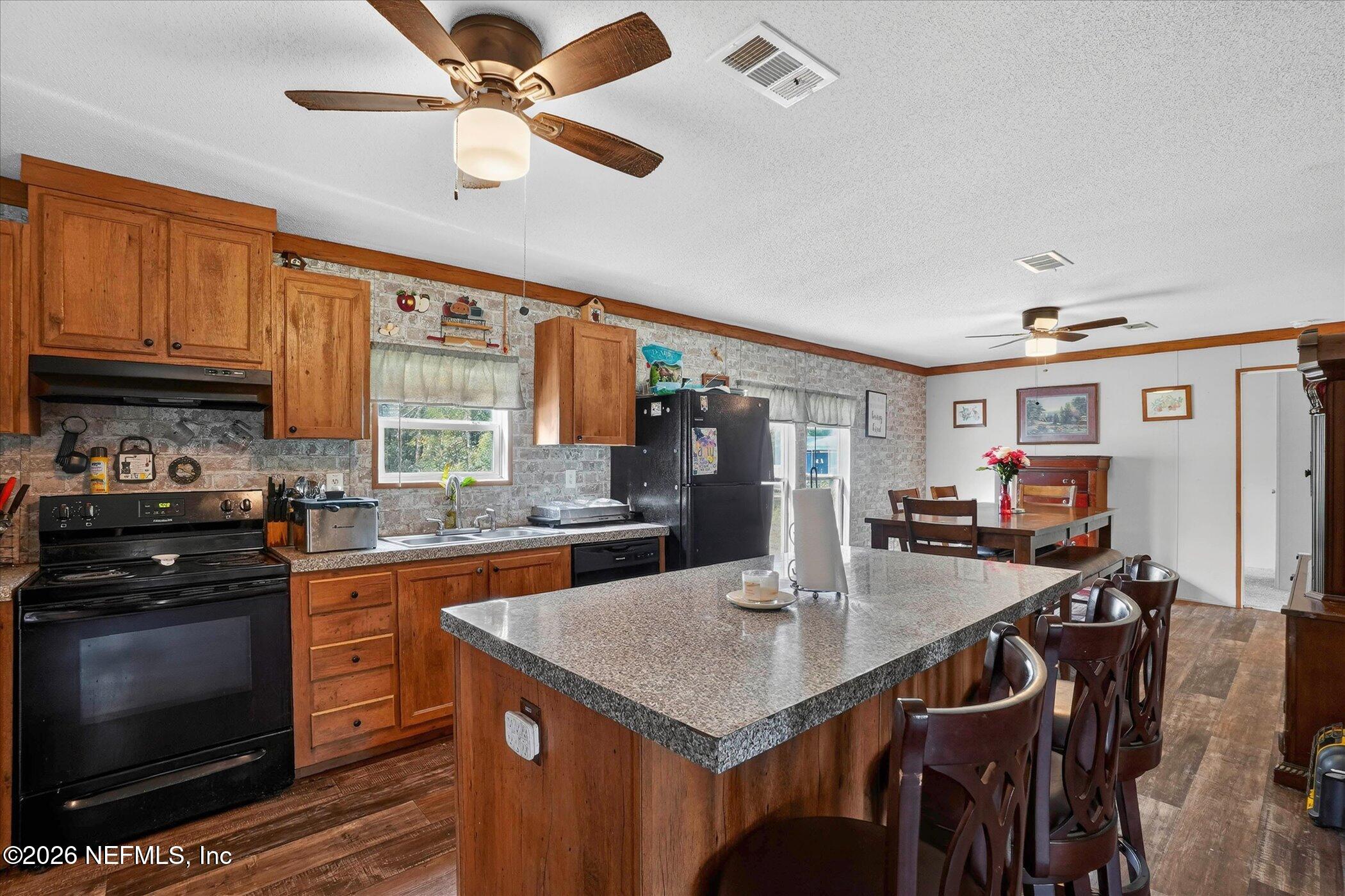85405 Blackmon Road Yulee, FL 32097 - Photo 9 of 27 a kitchen with stainless steel appliances granite countertop a stove a refrigerator a kitchen island with a stove and white cabinets