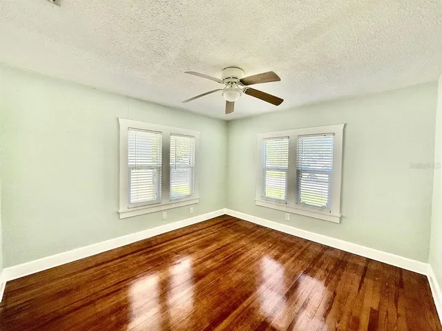 a view of an empty room with a window and wooden floor