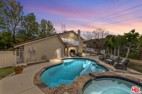 a view of a house with backyard swimming pool and sitting area