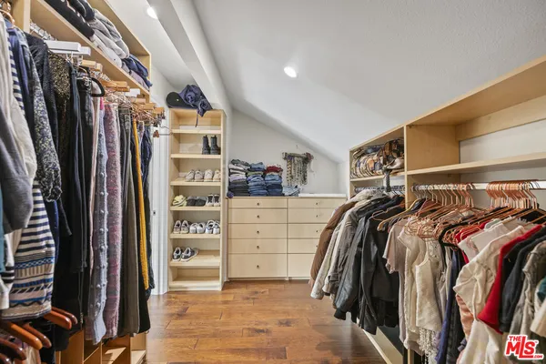 a view of walk in closet with clothes and shoes