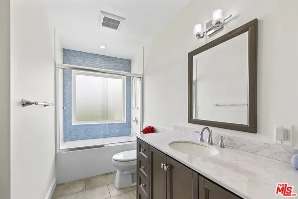 a bathroom with a granite countertop sink toilet a mirror and shower