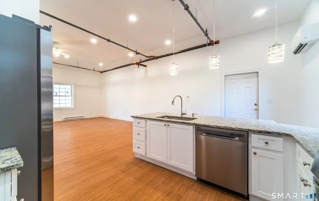 a kitchen with stainless steel appliances granite countertop a sink and cabinets with wooden floor