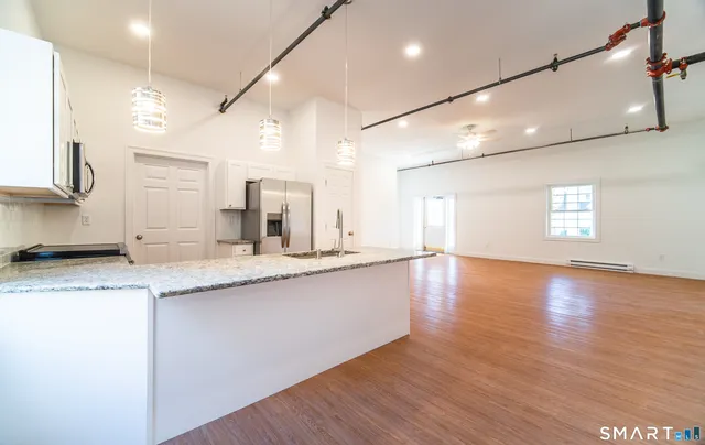 a large kitchen with stainless steel appliances granite countertop a sink a stove and a wooden floors