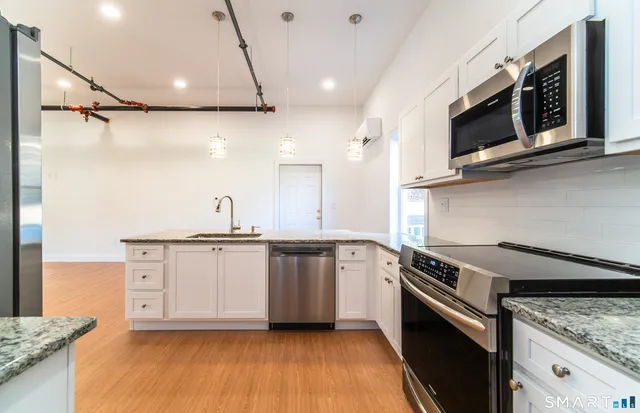 a kitchen with stainless steel appliances granite countertop a sink a stove and microwave
