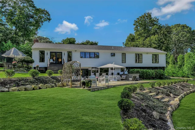 a front view of a house with garden and trees