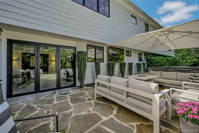 a view of a patio with couches table and chairs under an umbrella
