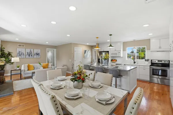 a view of a dining room and livingroom with furniture wooden floor a rug and a chandelier