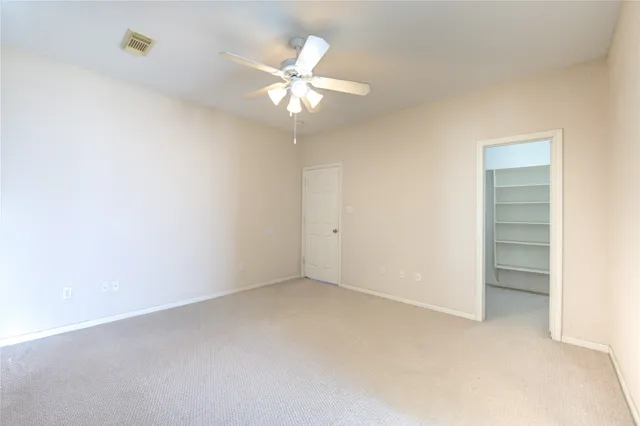 an empty room with a chandelier fan and closet