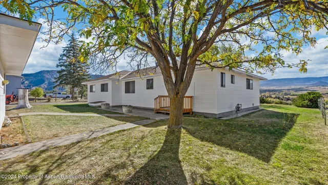 a view of a yard in front of a house with large trees