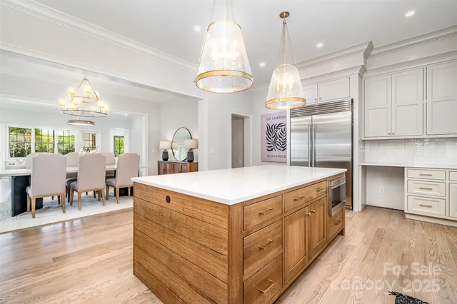 a large white kitchen with a large island oven a stove and a chandelier