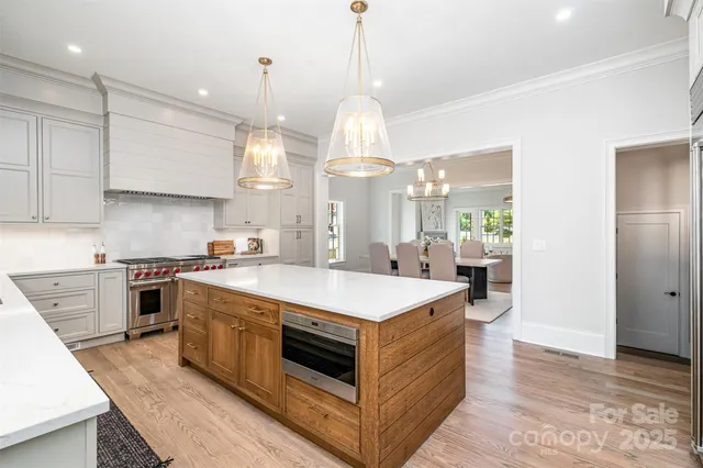 a large kitchen with stainless steel appliances granite countertop a sink a stove a refrigerator and island with wooden floor