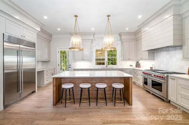 a kitchen with stainless steel appliances granite countertop a stove a sink a oven a refrigerator with island and chairs