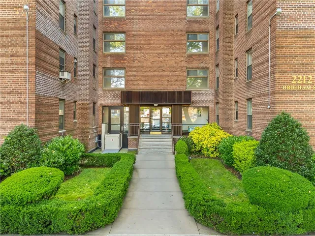 a view of a brick house with a yard and plants