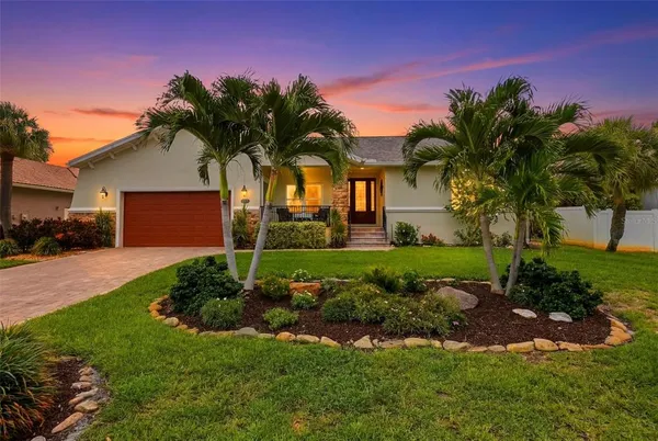a front view of a house with a garden and palm tree