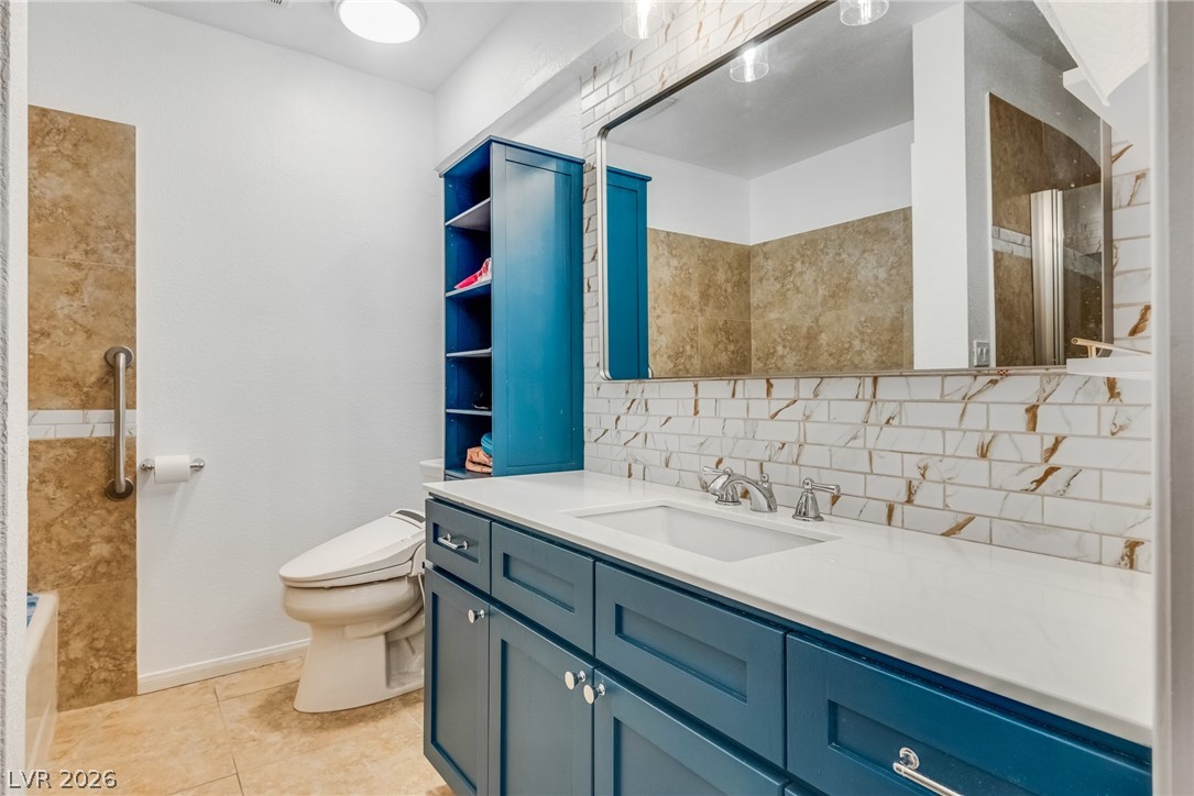 524 Swallow Cove Boulder City, NV 89005 - Photo 17 of 58 A refined bathroom features a stylish blue vanity, sleek white countertop, and subway tile backsplash.