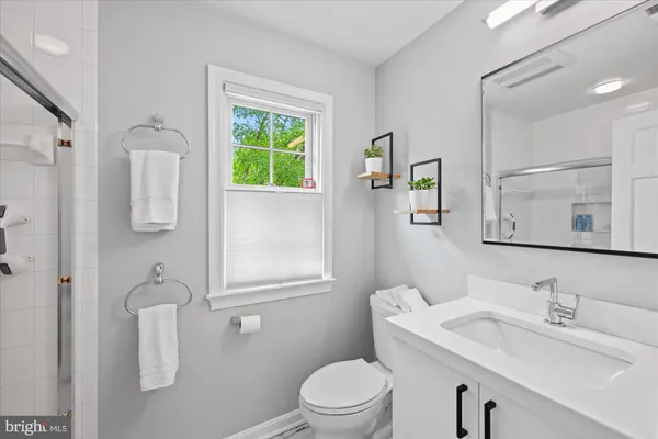 a bathroom with a toilet a sink a mirror and a window