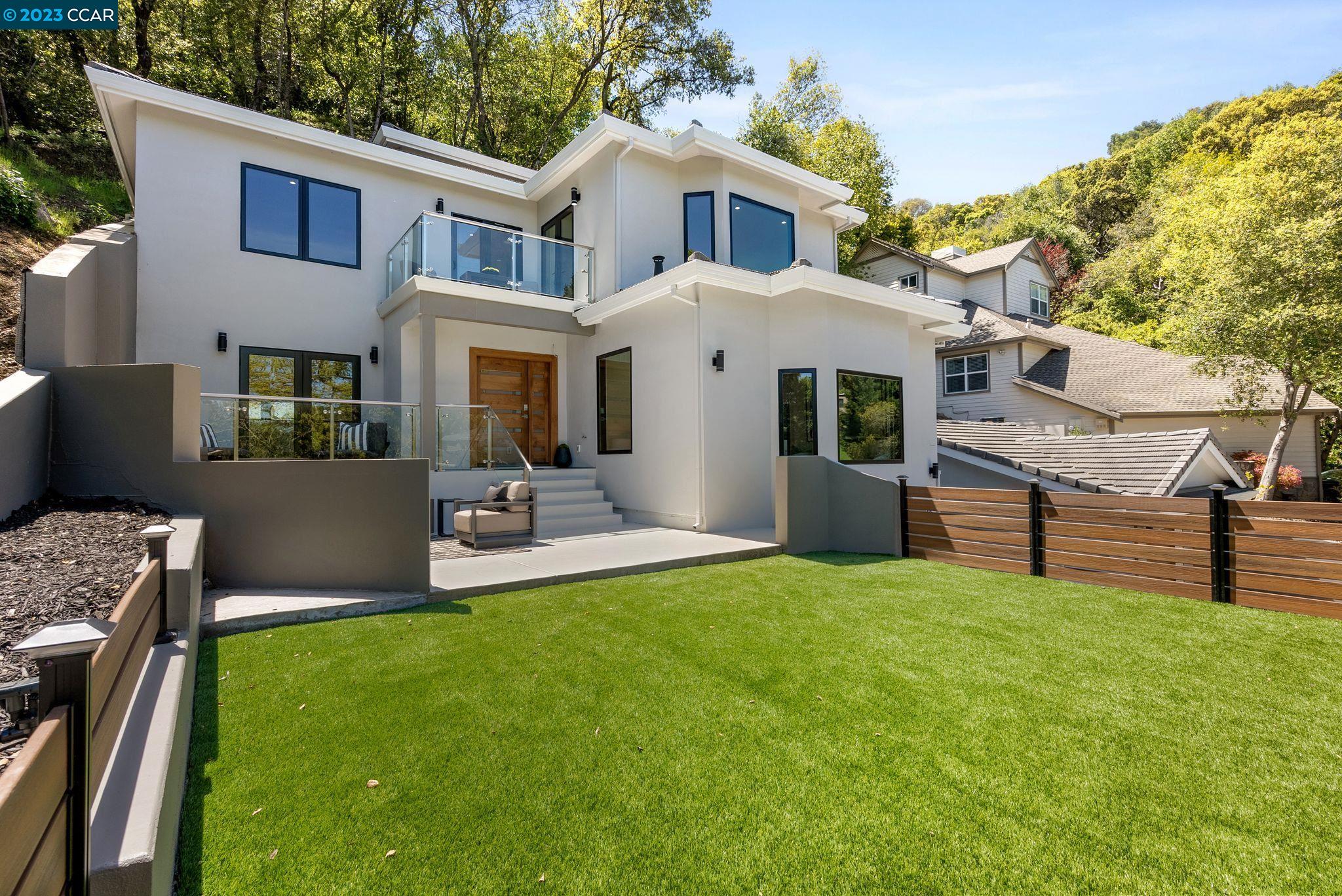 a view of a white house with a yard and sitting area