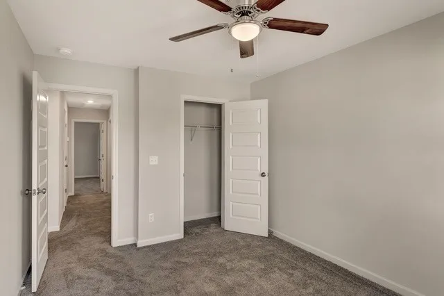 an empty room with closet and a ceiling fan