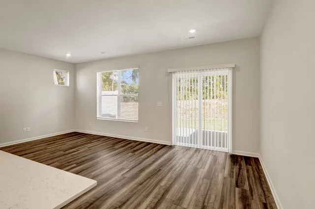 an empty room with wooden floor and windows