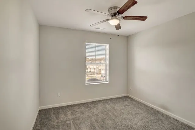 an empty room with a window and a fan